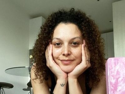 Mecia Simson is resting her head with the support of her hands.